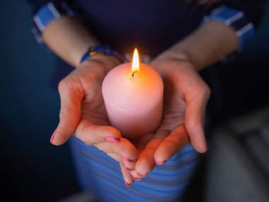 Yakından gelen çocukların elleri dua sırasında kilisede bir mum tutuyor..