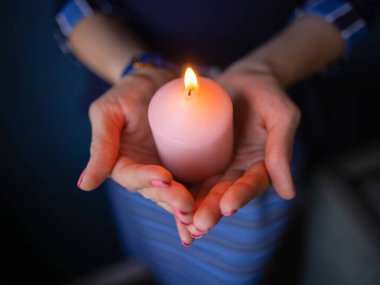 Yakından gelen çocukların elleri dua sırasında kilisede bir mum tutuyor..