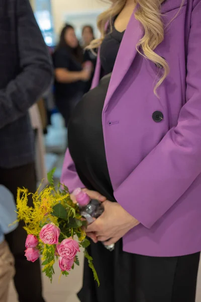 Zbliżenie piękne kobiety w ciąży s brzuch, trzymając kwiaty w rękach. — Zdjęcie stockowe