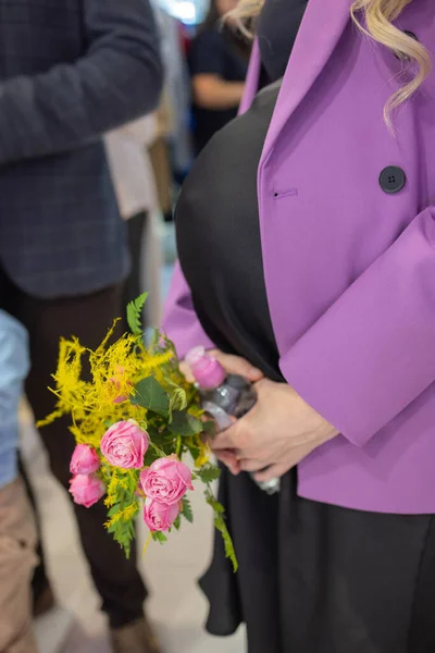 Close-up of a beautiful pregnant woman s belly, holding flowers in her hands. — Fotografia de Stock