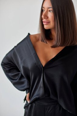 Young slim woman model in sunglasses, black military uniform stands with her legs wide apart and arms crossed at chest.