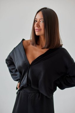 Young slim woman model in sunglasses, black military uniform stands with her legs wide apart and arms crossed at chest.