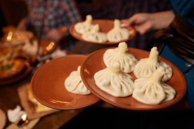 Eldiven giymiş bir garson elinde bir hinkali tutuyor..