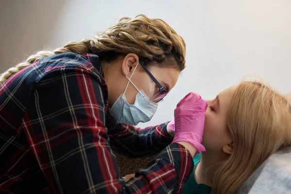 Professionale tenendo il gioiello del piercing poco prima di avvitare la palla. Tipo tragus . — Foto Stock