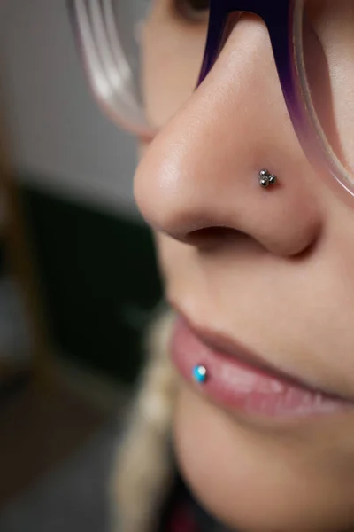 Close-up van een jonge vrouw gezicht met piercing septum opknoping uit haar neus. — Stockfoto