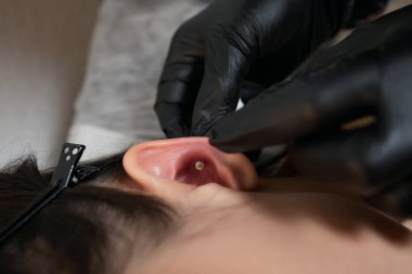 Kulağında piercing var. Şeytanminaresi ve sarmal piercingler.
