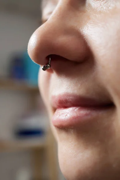 Primer plano del rostro de una joven mujer con el tabique perforado colgando de su nariz. — Foto de Stock