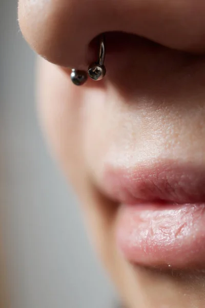 Primo piano di un giovane volto femminile con piercing al setto appeso al naso. — Foto Stock