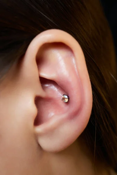 Piercings op een oor. Conch en helix piercings close-up. — Stockfoto