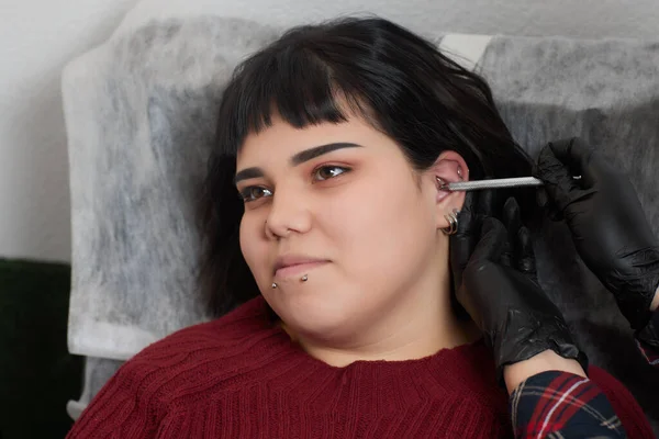 Profissional segurando a jóia do dia piercing pouco antes de parafusar a bola. Tipo de trágico. — Fotografia de Stock