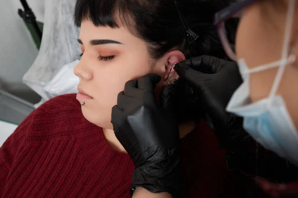 Professional holding the jewel of piercing day just before screw the ball. Tragus type. — Stock Photo, Image
