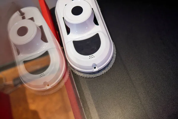 Desvantagem do robô aspirador de pó para lavar janela de vidro e controle remoto sobre fundo cinza. Assistente de robô em casa para limpar janelas. — Fotografia de Stock
