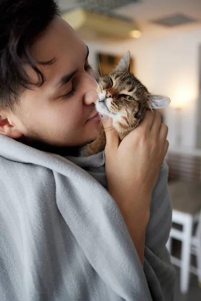 Mladý muž v tričku drží kočku. — Stock fotografie
