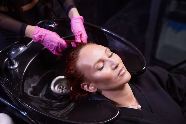Peluquería en el salón de belleza lava el cabello de su cliente, antes del procedimiento de aplicación de ingredientes naturales de restauración y vitaminas para el cabello y corte de pelo. — Foto de Stock