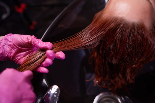 Kapster in schoonheidssalon wast zijn klant haar, voor de procedure van het aanbrengen van natuurlijke restauratie ingrediënten en vitaminen op haar en kapsel. — Stockfoto