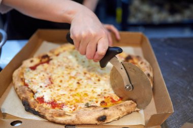 Mutfakta pizza kesen beyaz üniformalı aşçının yakın çekimi..