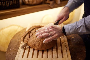 Ahşap masa, seçici odak üzerinde kesme buğday ekmek erkek eller.