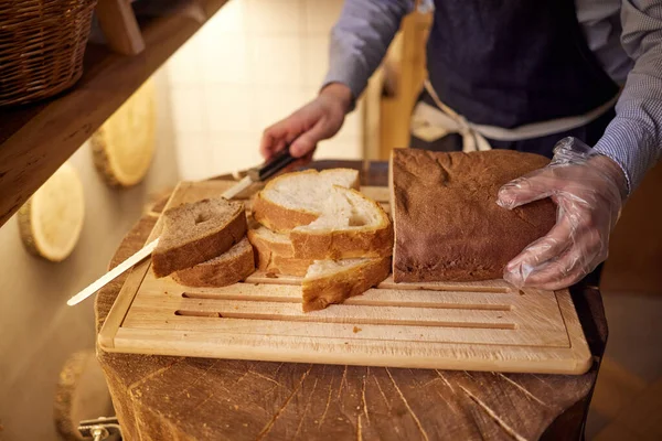 Mains masculines coupant du pain de blé sur la planche de bois, mise au point sélective . — Photo