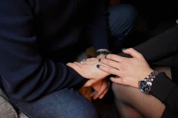 Cropped shot of young couple holding hands while sitting together. Focus on hands. — Stock Photo, Image