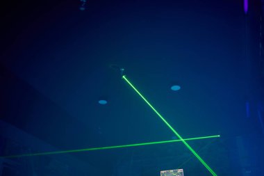 Parlak yeşil neon lazer ışıkları karanlığı aydınlatır. Bilim kurgu efektiyle çizgiler ve üçgen şekiller yaratır..
