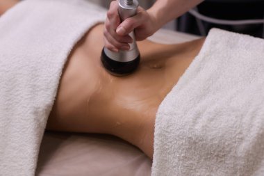 Kadın karın bölgesindeki selüliti, karın masajını kaldırma prosedürü. Kilo vermek için ultrasonik masaj. Cerrahi müdahale olmadan kadın figürünün düzeltilmesi. Karnına yakın çekim..