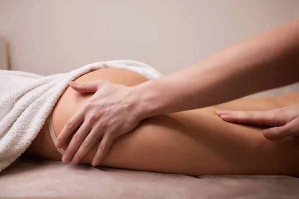 Крупним планом масажистські руки наливають масажну олію до спини жінки, готуючись до розслабляючого або оживляючого масажу . — стокове фото