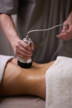 Kadın karın bölgesindeki selüliti, karın masajını kaldırma prosedürü. Kilo vermek için ultrasonik masaj. Cerrahi müdahale olmadan kadın figürünün düzeltilmesi. Karnına yakın çekim..