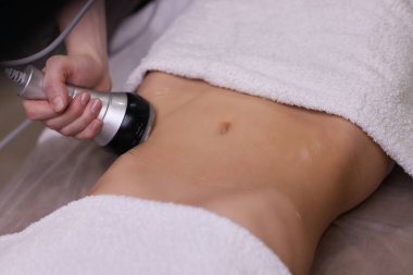 Kadın karın bölgesindeki selüliti, karın masajını kaldırma prosedürü. Kilo vermek için ultrasonik masaj. Cerrahi müdahale olmadan kadın figürünün düzeltilmesi. Karnına yakın çekim..