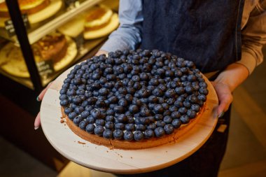 Taze pişmiş bireysel yabanmersini turtası ve taze böğürtlen. Arka plan olarak ahşap bir masa. Yukarıdan doğal yönlü ışıklandırma ile yakın çekim.