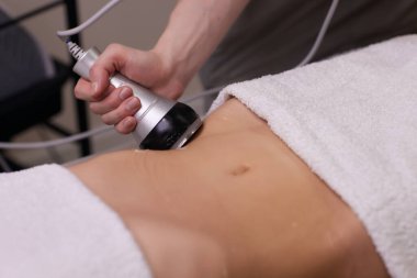 Kadın karın bölgesindeki selüliti, karın masajını kaldırma prosedürü. Kilo vermek için ultrasonik masaj. Cerrahi müdahale olmadan kadın figürünün düzeltilmesi. Karnına yakın çekim..