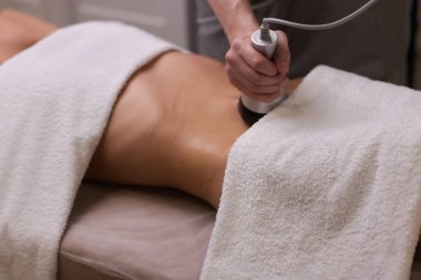 Kadın karın bölgesindeki selüliti, karın masajını kaldırma prosedürü. Kilo vermek için ultrasonik masaj. Cerrahi müdahale olmadan kadın figürünün düzeltilmesi. Karnına yakın çekim..