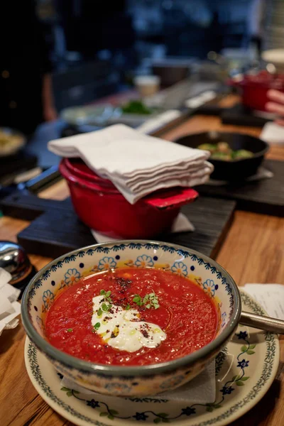 Sopa georgiana rica en kharcho con carne en un plato de naranja profundo en una tabla de madera con hierbas y cereza, cebolla y ajo en la mesa. —  Fotos de Stock