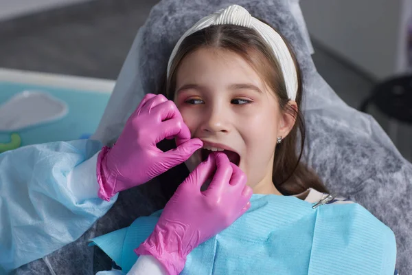 Corte as mãos vista em luvas de látex para fio dental dentes da frente da criança. Mulher segurar ferramentas dentárias ao lado . — Fotografia de Stock