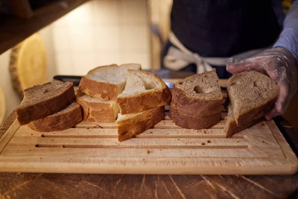 Mains masculines coupant du pain de blé sur la planche de bois, mise au point sélective . — Photo