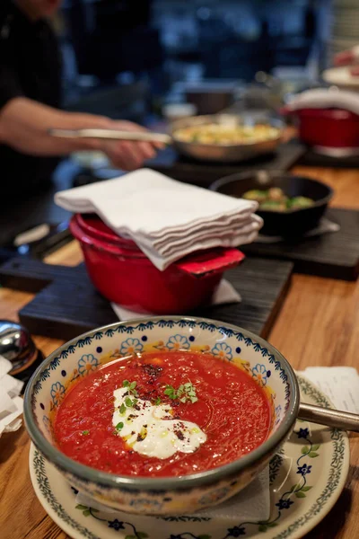 Sopa georgiana rica en kharcho con carne en un plato de naranja profundo en una tabla de madera con hierbas y cereza, cebolla y ajo en la mesa. — Foto de Stock