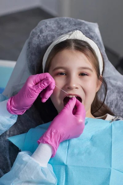 Tagli mani di vista in guanti di lattice per filare denti anteriori di bambino. Donna tenere strumenti dentali accanto . — Foto Stock