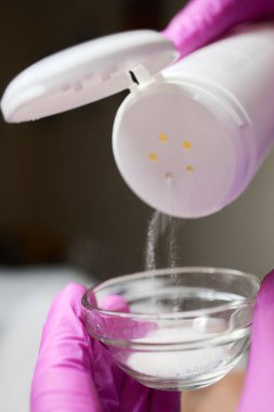 Kadın eli Gri Arkaplanda talk pudrası kullanıyor.