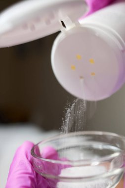 Kadın eli Gri Arkaplanda talk pudrası kullanıyor.