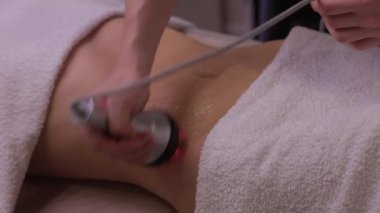 Kadın karın bölgesindeki selüliti, karın masajını kaldırma prosedürü. Kilo vermek için ultrasonik masaj. Cerrahi müdahale olmadan kadın figürünün düzeltilmesi. Karnına yakın çekim..