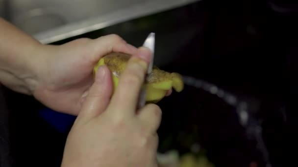 Zbliżenie rąk mans obieranie złotego ziemniaka i usuwanie skórki warzyw z obieraczki do ziemniaków. — Wideo stockowe