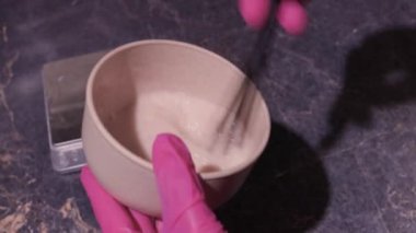 Beyaz lastik eldivenli kız elinde fırça tutuyor ve saç boyasını karıştırıyor. Saç maskesinde saç bakımı yapıyor..