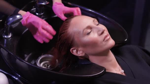 Güzellik salonundaki kuaför, saç ve saç kesimine doğal yenileme malzemeleri ve vitaminler uygulamadan önce müşterisinin saçını yıkar.. — Stok video