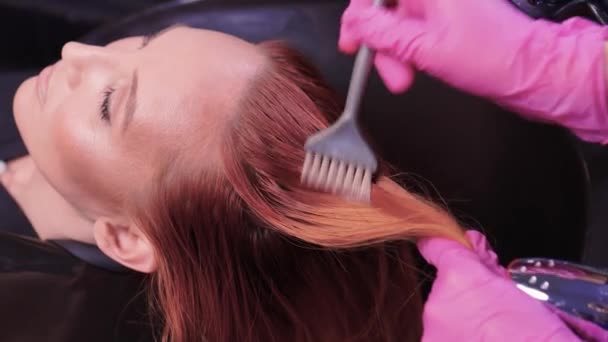 Güzellik salonundaki kuaför, saç ve saç kesimine doğal yenileme malzemeleri ve vitaminler uygulamadan önce müşterisinin saçını yıkar.. — Stok video