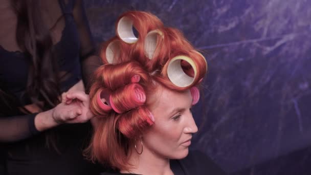Крупный план рыжих волос во время одевания волос с бигуди. — стоковое видео