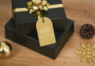 Siyah hediye kutusu ve sahte Noel kutlaması Ahşap masa arka planında etiketler.
