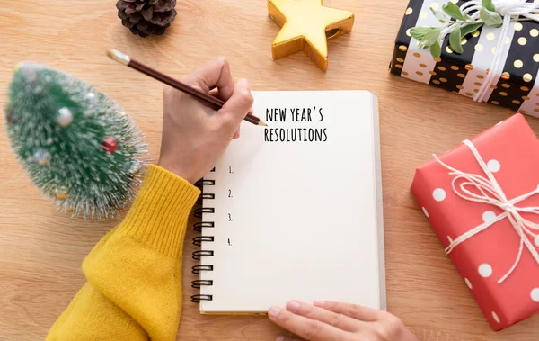 Woman hand writing New year\'s resolution on note paper in new year day.