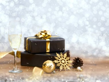 Bokeh arka planında süslemeleri olan Noel hediyesi kutusu ve şampanyamız..