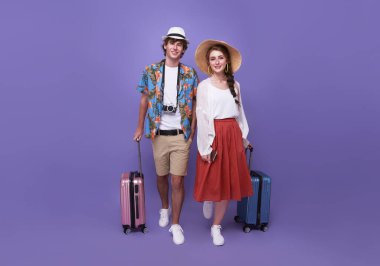 Bagajı olan mutlu çift, mor arka planda izole tatillerde seyahate çıkıyor. Tatil zamanı.