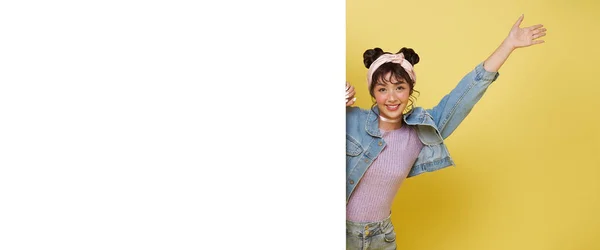 陽気若いアジアの女性は黄色の背景に白い空白のバナーや空のコピースペース広告ボードの後ろに立っています — ストック写真