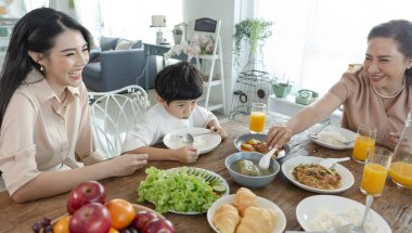 Asyalı mutlu aile birlikte öğle yemeği yiyerek vakit geçiriyor. Evde ilişki ve aktivite.
